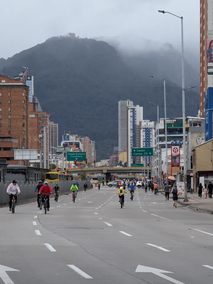 Ciclistas ocupando los carriles de una avenida cerrada durante la Ciclovía, con los cerros orientales al fondo